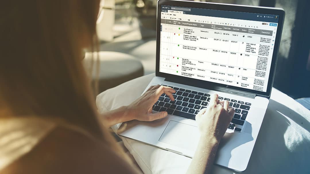 A business woman views Smartsheet in grid view on a laptop